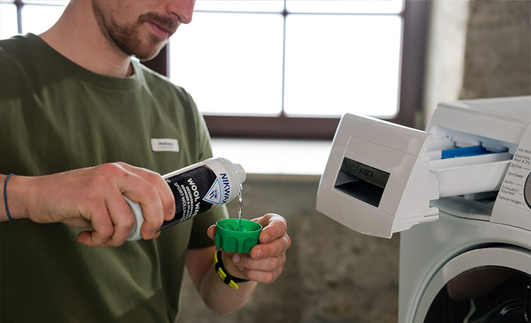 merinowol wassen met wolwasmiddel Man doet wolwasmiddel in de wasmachine