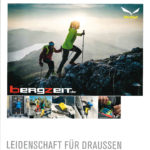 Zwei Trailrunner/Wanderer mit St&ouml;cken laufen auf felsigem Untergrund einen Berg hinauf in der D&auml;mmerung