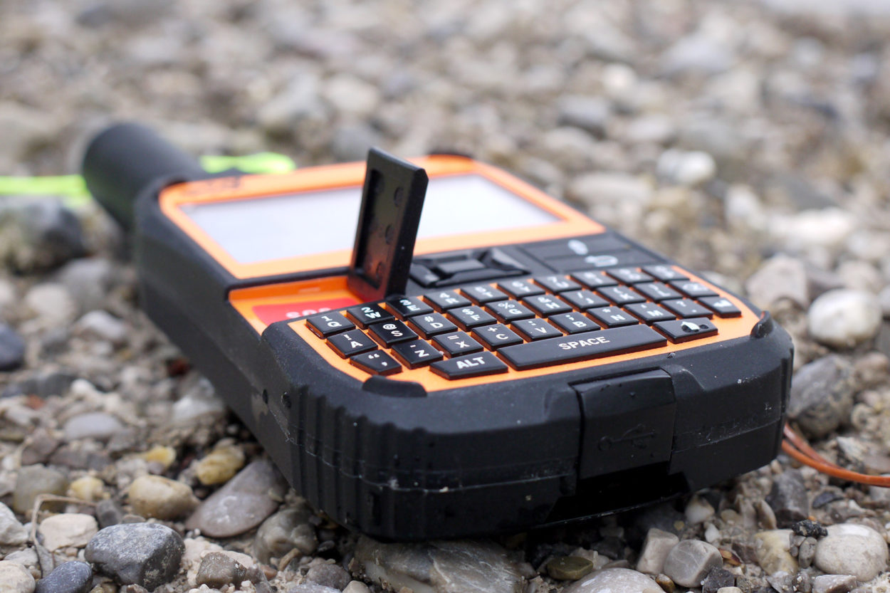 Nahaufnahme des Spot X mit der Tastatur und aufgeklapptem Deckel der Notfalltaste.