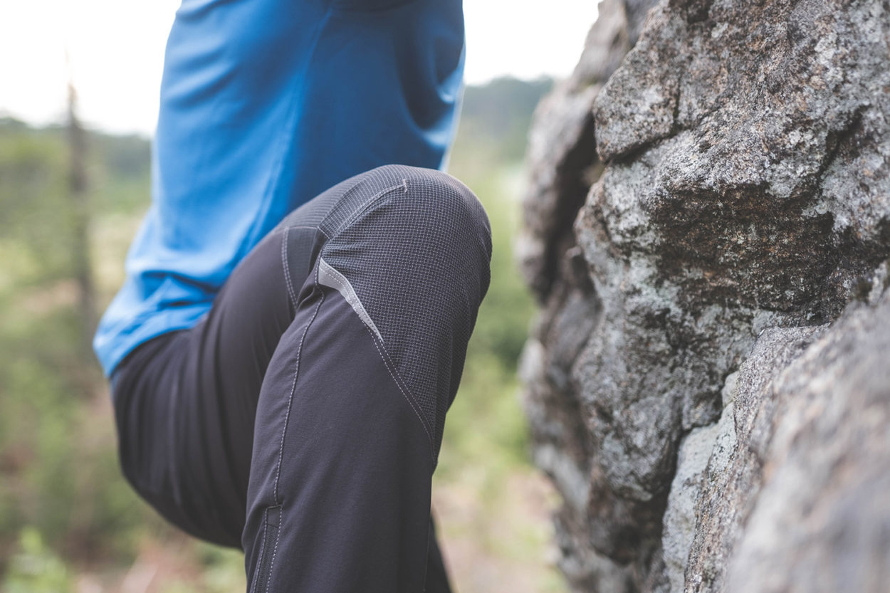 Knieausschnitt eines Mannes beim Bouldern mit dehnbarer Kletterhose.