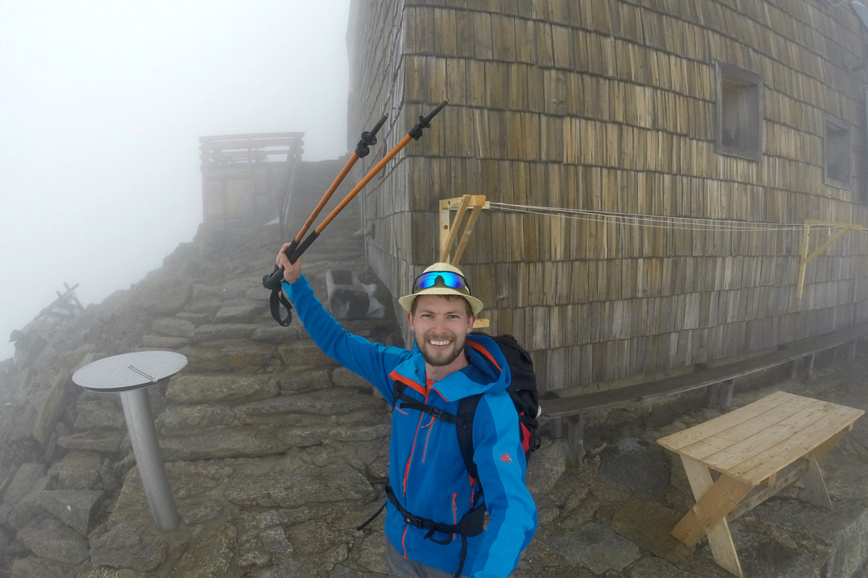 Ein fröhlicher Bergsteiger im Nebel vor dem Becherhaus.
