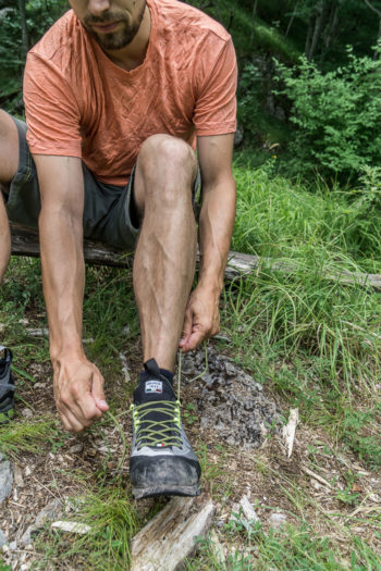 Wanderer sitzt auf Stein und schnürt seinen Schuh