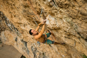 Kletterer in rötlichem Kalkstein und Überhang