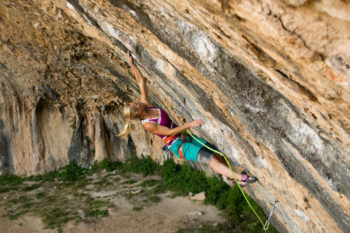Kletterin in rötlichem Kalkstein in überhängender Wand