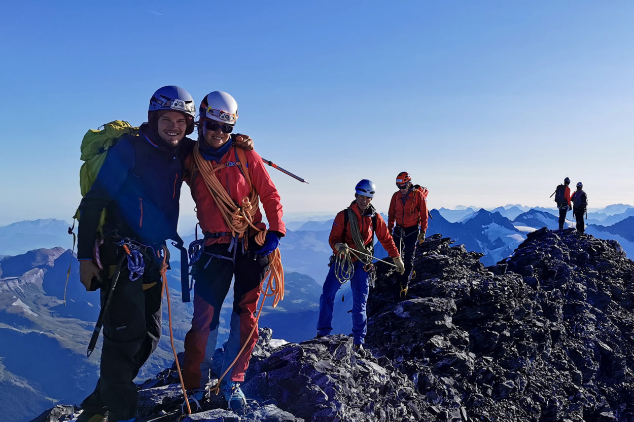 Zwei Bergsteiger posieren für ein Foto auf dem Gipfel.