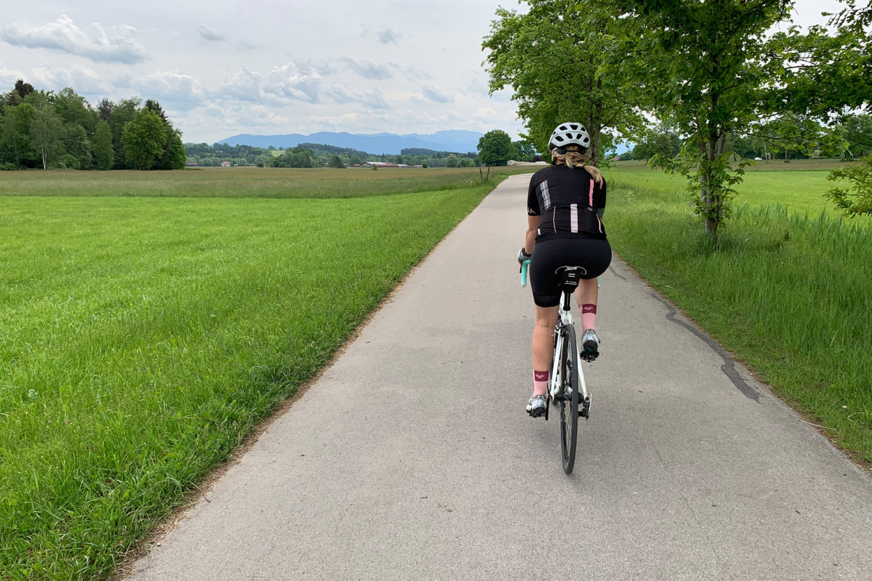 Rennradfahrerin unterwegs Richtung Berge.